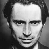 A black and white headshot of Robert Carlyle